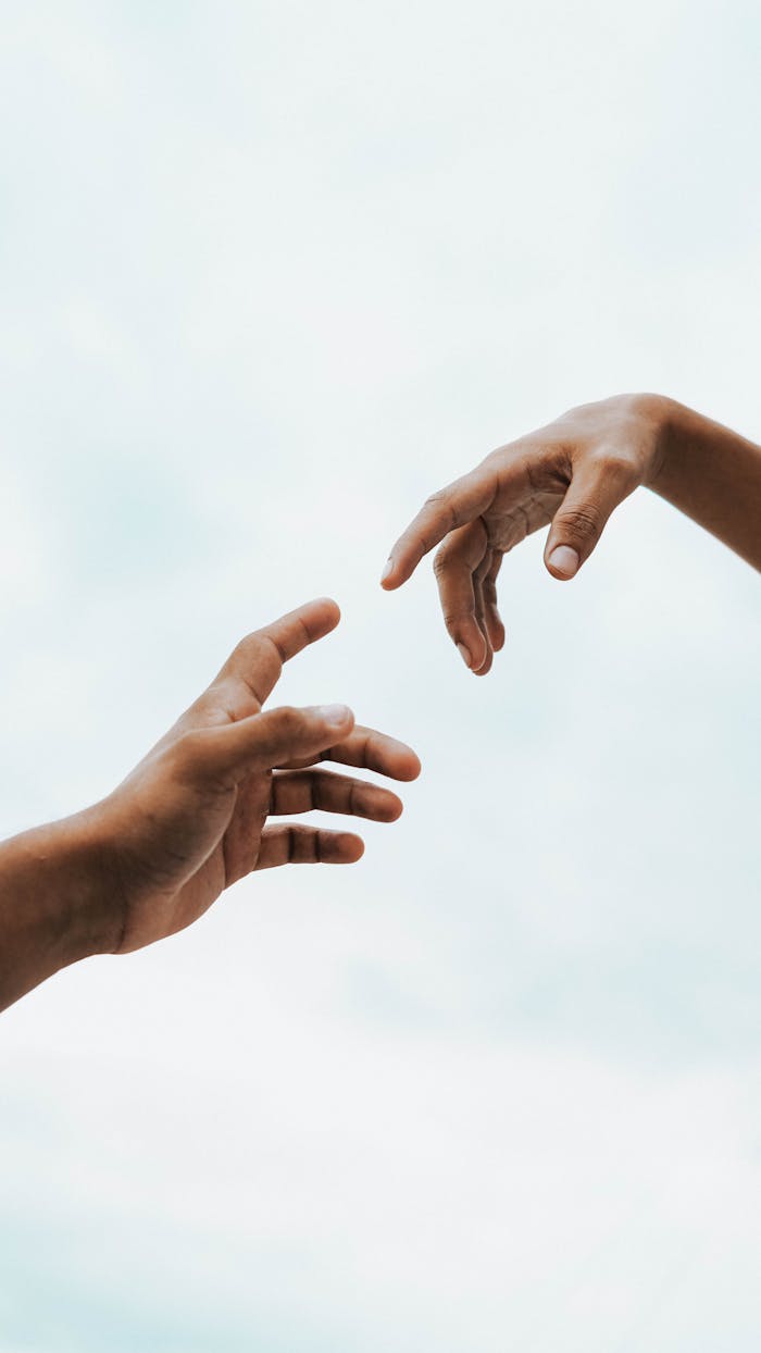 Crafting Captivating Headlines: Your awesome post title goes here Two hands reaching toward each other against a bright sky, symbolizing connection and unity.