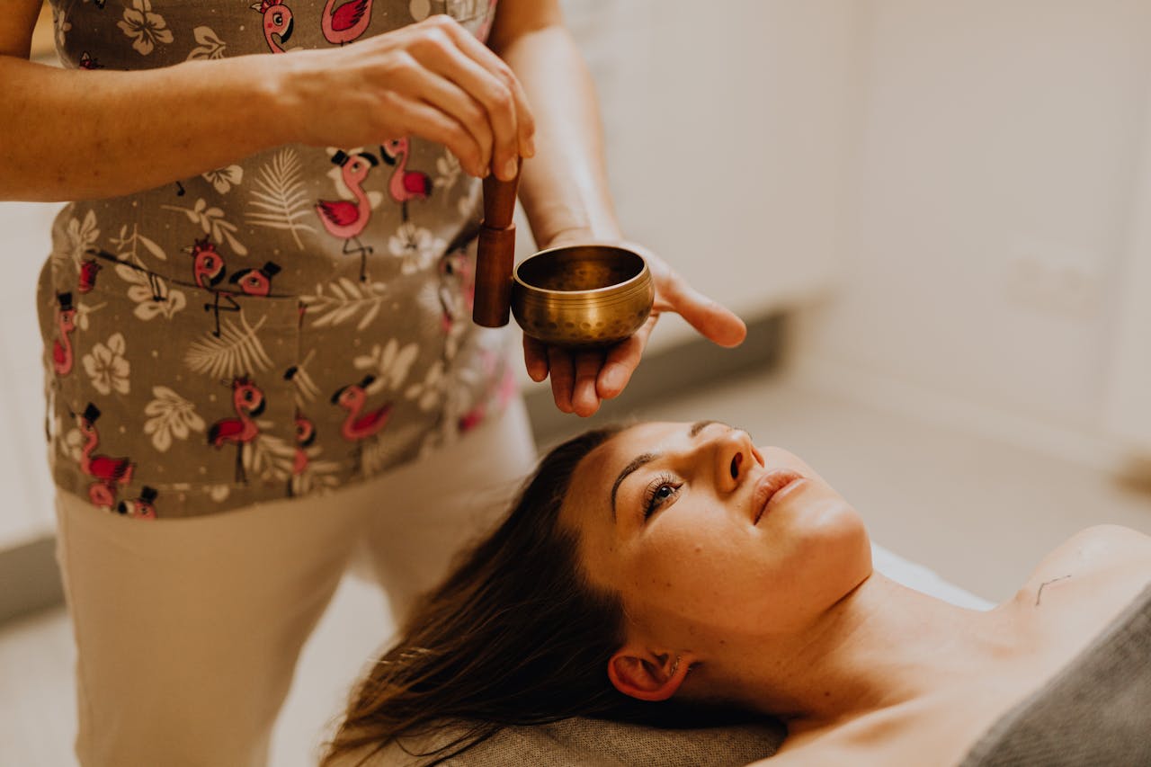 why-choose-us-02 Young woman experiencing relaxation therapy with a singing bowl indoors.