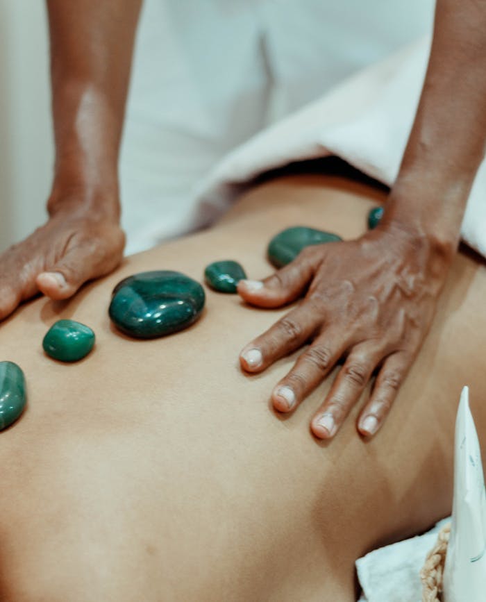services-01 Hands performing a soothing hot stone massage with therapeutic stones on bare back.